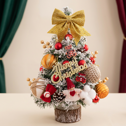 Snowy tabletop tree with golden bow and red orange ornaments
